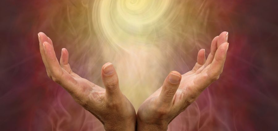a pair of hands holding a swirling ball of light - an aura