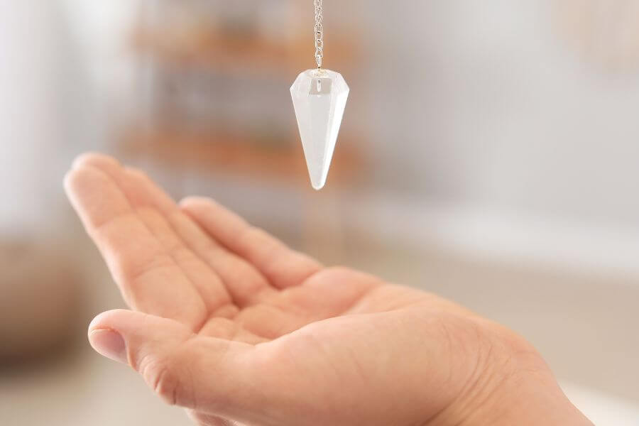 A psychic reader's hand lay out flat, palm facing upwards whilst swinging a pendulum