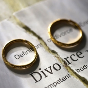 two wedding rings lay on top of split paper saying Divorce
