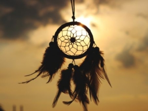 a dream catcher silhouette dangling in the sunset