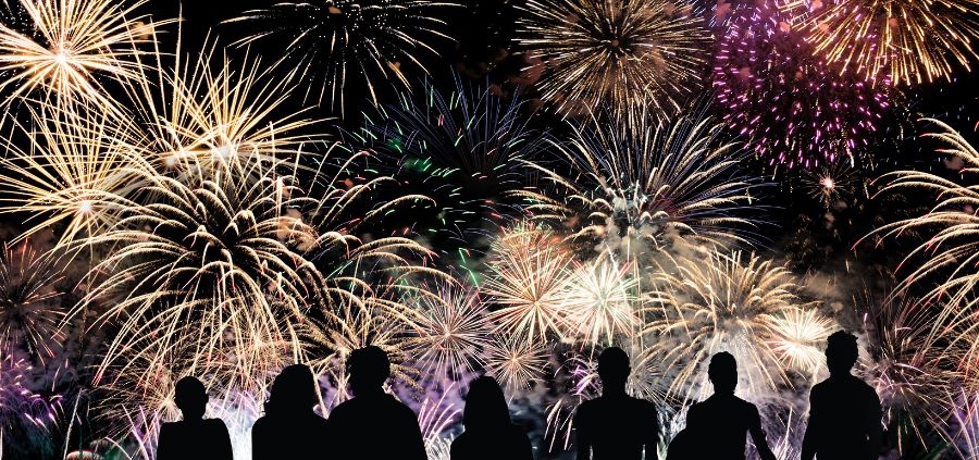 Silhouette of a group of people watching fireworks.