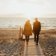 An image of a couple walking on a board walk on a beach.