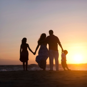 a family holding hands on the beach in the sunset