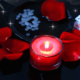 Red candle surrounded by petals and playing cards