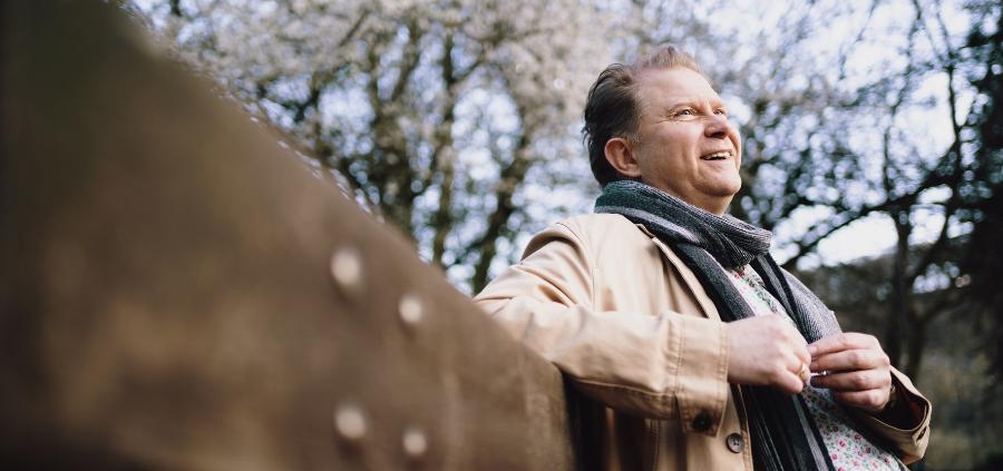 A man deep in though, sat on a park bench in a winter scene