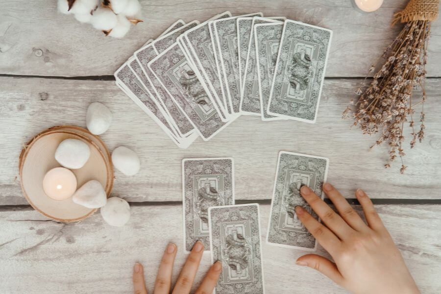 a pair of hards touching some grey oracle cards on a wooden table