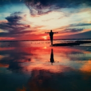 Person standing with arms out during sunset