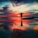 Person standing with arms out during sunset