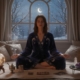 A female psychic reader sat in her living room, performing a spiritual psychic reading. A big open window shows a moon
